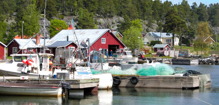 Ett litet fiskeläge med några fiskebåtar och ett båthus vid vatten. Foto.